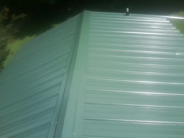 New green metal panels meeting at the ridge of a roof — Flat Roof Repair work by our crew in Coal Township