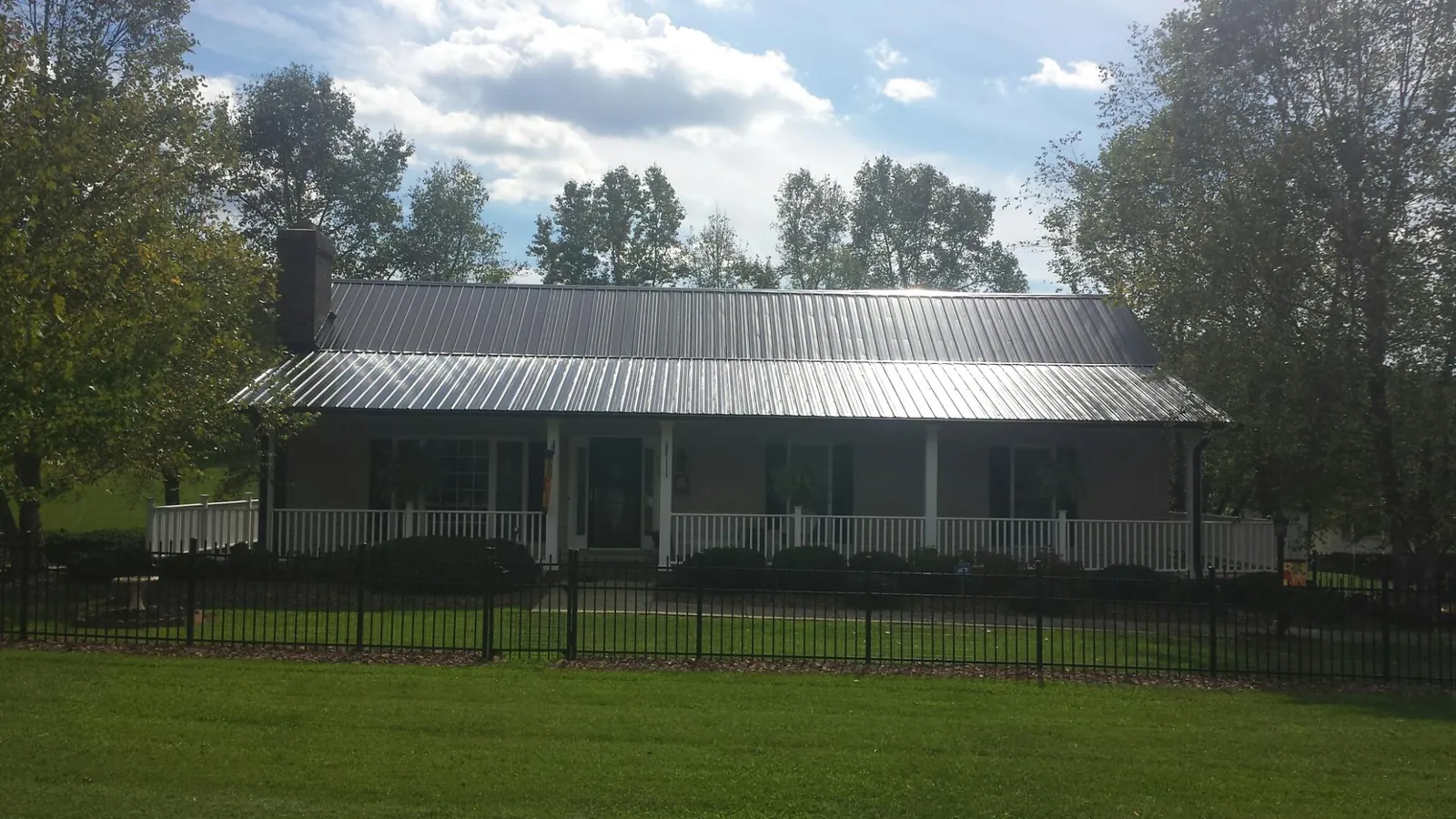 Gray metal roof on a brick ranch with a full width front porch — Gutter Guard Installation work by our crew in Coal Township