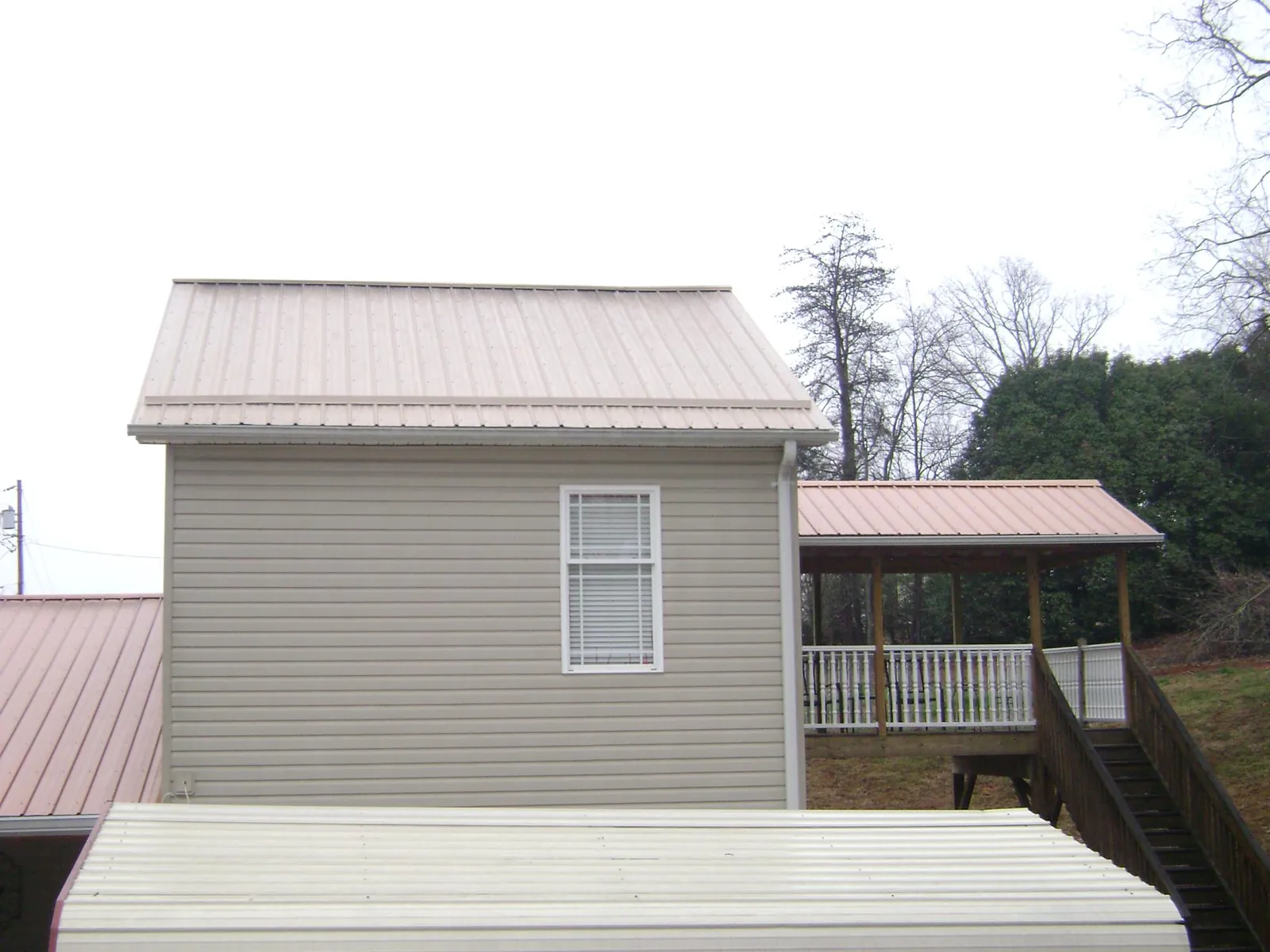 Tan metal roofs on a two story addition and attached porch, from a Roof Replacement job in Coal Township