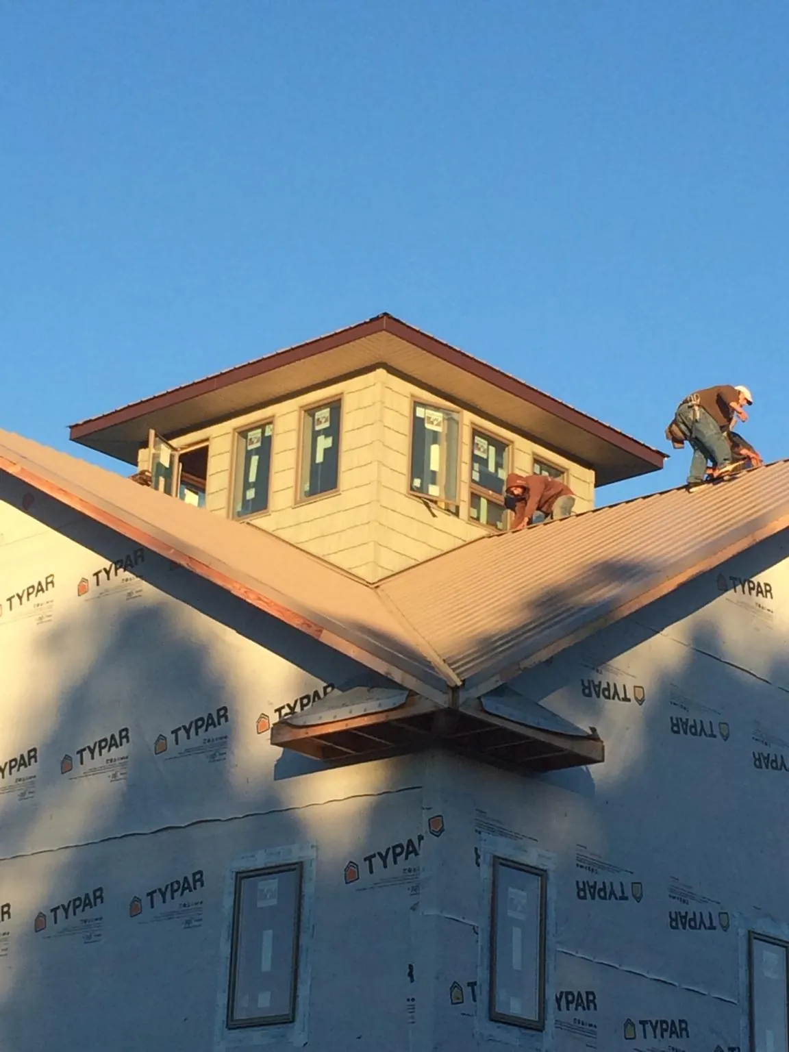 Roofers working around a rooftop cupola on a new metal roof at sunset — Roof Waterproofing in Coal Township by Roofing Brothers